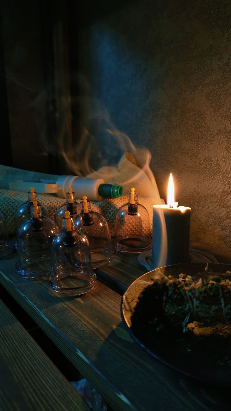 Ventouses en verre, bougie allumée et volutes de fumée, ambiance chaleureuse et feutrée