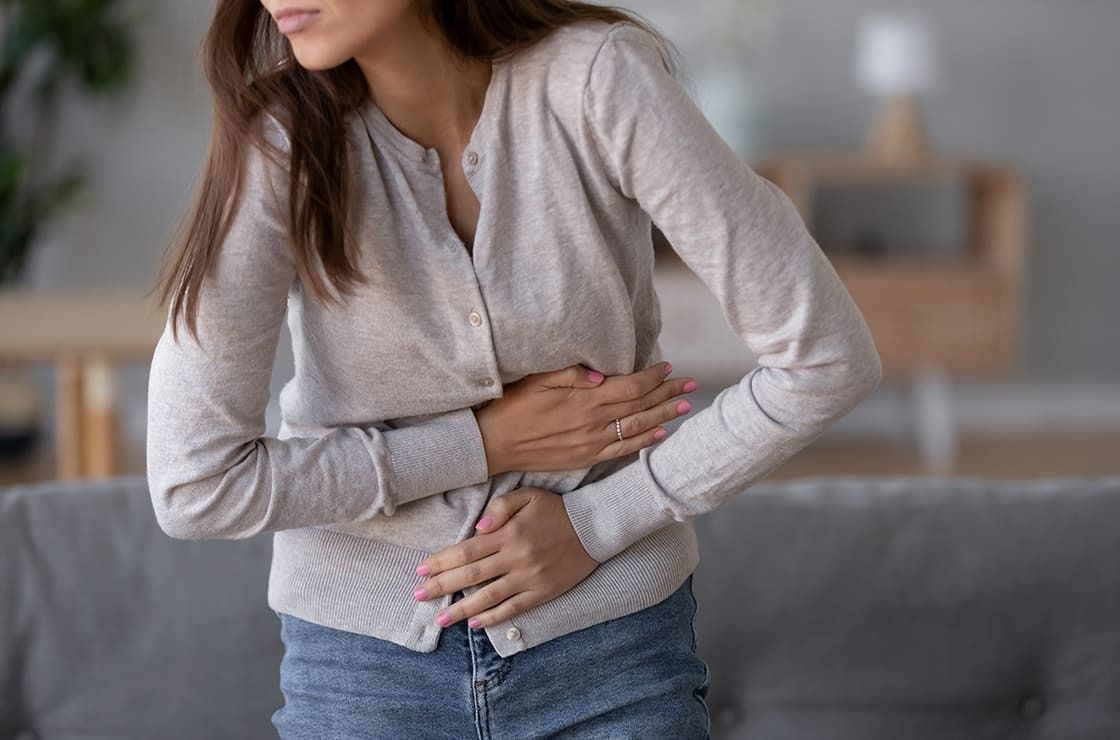 Femme portant la main à son ventre, troubles digestifs